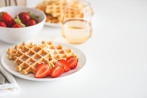 Belgian waffles with strawberry and powdered sugar on white plate. Breakfast food concept. Copy space