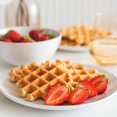 Beyaz tabakta çilekli Belçika waffleları. Kahvaltı konsepti.