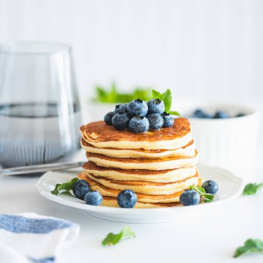 Beyaz ahşap masada taze böğürtlenli ev yapımı ricotta krepleri.