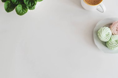 Tablet, akıllı telefon, defter, kahve fincanı, yiyecek ve bitki ile beyaz masaya. Üst Manzara. Düz yatıyordu