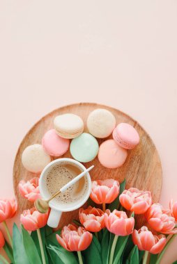 Bir buket pembe lale, bir fincan kahve ve pembe arka planda badem kurabiyesi. Yıldönümü kutlaması. Uzayı kopyala Üst görünüm