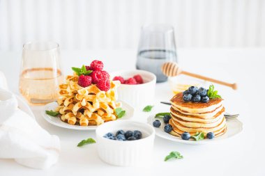 Yaz kahvaltısı. Ev yapımı ricotta krepleri ve beyaz ahşap masada taze böğürtlenli Belçika waffle 'ları.