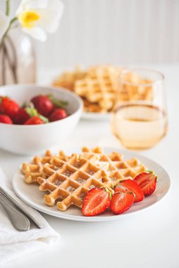 Çilekli Belçika waffle 'ları ve beyaz tabakta pudra şekeri. Kahvaltı konsepti.