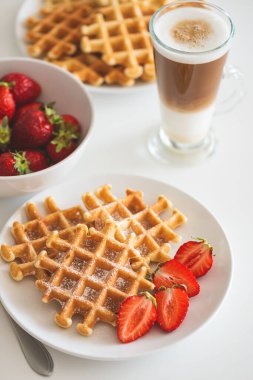 Çilekli Belçika waffleları ve beyaz tabakta kahve. Kahvaltı konsepti.