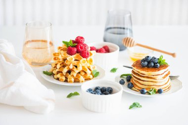 Yaz kahvaltısı. Ev yapımı ricotta krepleri ve beyaz ahşap masada taze böğürtlenli Belçika waffle 'ları.
