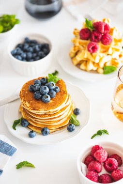 Yaz kahvaltısı. Ev yapımı ricotta krepleri ve beyaz ahşap masada taze böğürtlenli Belçika waffle 'ları.