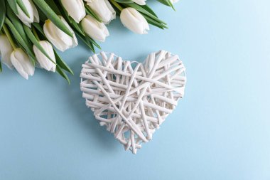Beyaz lale buketinden çiçek sınırı ve mavi arka planda ahşap kalp. Yıldönümü kutlaması. Üst görünüm