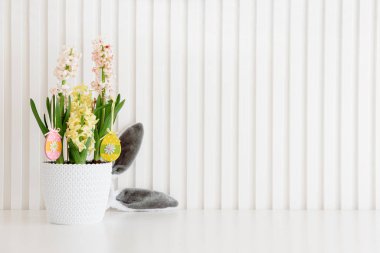 Sümsük çanağı süslü Paskalya ahşap yumurtaları ve tavşan beyaz arka planda oyuncaklar duyuyor. Paskalya kutlaması. Uzayı kopyala Ön görünüm