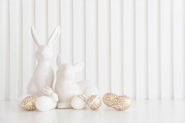Beyaz arka planda Paskalya tavşanları heykelcikleri ve yumurtalar. Paskalya kutlaması. Uzayı kopyala Ön görünüm