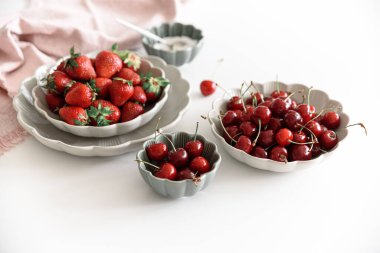 Taze yaz meyvelerini beyaz masada kaselere koyarız. Yaz yemekleri konsepti. Yumuşak odak