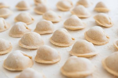 Beyaz masada pişmemiş ev yapımı pelmeni. Pelmeni, ravioli veya etli hamur tatlısı yapma süreci