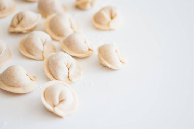 Beyaz masada pişmemiş ev yapımı pelmeni. Pelmeni, ravioli veya etli hamur tatlısı yapma süreci