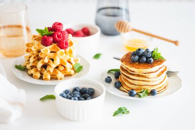 Yaz kahvaltısı. Ev yapımı ricotta krepleri ve beyaz ahşap masada taze böğürtlenli Belçika waffle 'ları.