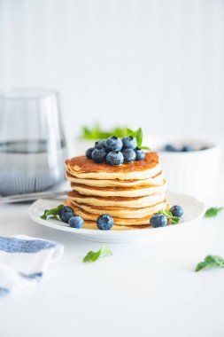 Beyaz ahşap masada taze böğürtlenli ev yapımı ricotta krepleri.