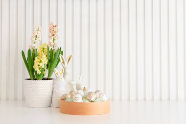 Beyaz arka planda sümbül ve yumurta dolu Paskalya tavşanları heykelcikleri. Paskalya kutlaması. Uzayı kopyala Ön görünüm