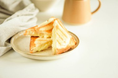 Erimiş peynirli sandviç parçaları beyaz masada.