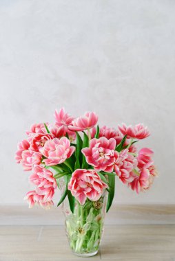 Ahşap arka planda vazoya pembe lale buketi. Yıldönümü kutlaması. Uzayı kopyala Ön görünüm