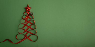 Kırmızı kurdele ve yeşil arka planda yıldız şeklindeki oyuncaktan yapılmış Noel ağacı. Üst manzara. Düz yatıyordu