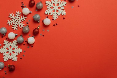 Kar taneleri ve parıltılı süslemelerle dolu kırmızı Noel arkaplanı. Noel ve Yeni Yıl Kutlama Konsepti. Üst görünüm