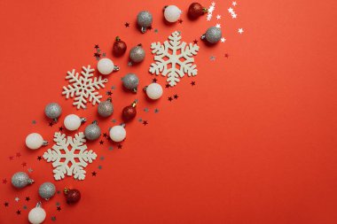 Kar taneleri ve parıltılı süslemelerle dolu kırmızı Noel arkaplanı. Noel ve Yeni Yıl Kutlama Konsepti. Üst görünüm