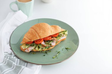 Beyaz masada marul, peynir, jambon ve mikroçerez ile kruvasan tostu. Sağlıklı kahvaltı. Üst görünüm