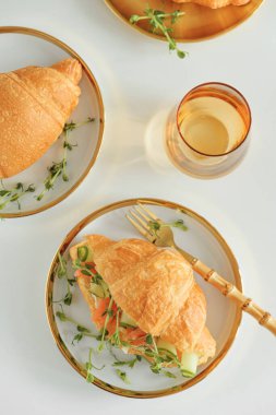 Somonlu kruvasan sandviç, beyaz masada soğan ve mikroyeşillik. Sağlıklı kahvaltı. Üst görünüm