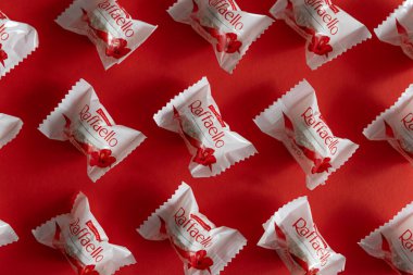 Lviv, Ukrayna - Şubat 2025: Kırmızı arka planda Raffaello çikolatalı kurabiyeler. Ürün üst görünüm çekim