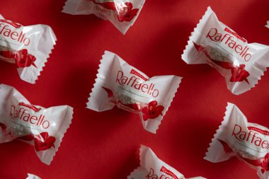 Lviv, Ukrayna - Şubat 2025: Kırmızı arka planda Raffaello çikolatalı kurabiyeler. Ürün üst görünüm çekim