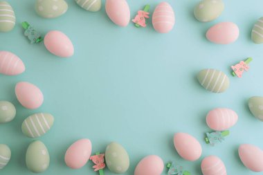 Paskalya yumurtaları ve pastel arka planda bahar çiçekleri. Üst görünüm