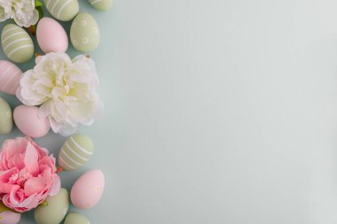 Paskalya yumurtaları ve pastel arka planda bahar çiçekleri. Üst görünüm