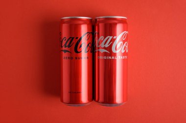 Lviv, Ukrayna - 25 Mart 2025: Demir kutular dolusu Coca Cola klasiği ve kırmızı zemin üzerinde Coca Cola sıfır şeker. Üst görünüm