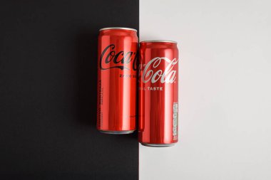 Lviv, Ukrayna - 25 Mart 2025: Demir kutular dolusu Coca Cola klasiği ve Coca Cola sıfır şekerli siyah beyaz arka plan. Üst görünüm