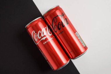 Lviv, Ukrayna - 25 Mart 2025: Demir kutular dolusu Coca Cola klasiği ve Coca Cola sıfır şekerli siyah beyaz arka plan. Üst görünüm