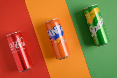 Lviv, Ukrayna - 25 Mart 2025: Renkli arka planda demir Coca Cola, Fanta ve Sprite içecekleri. Üst görünüm