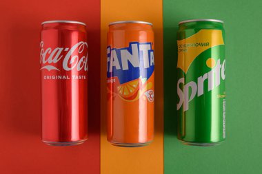 Lviv, Ukrayna - 25 Mart 2025: Renkli arka planda demir Coca Cola, Fanta ve Sprite içecekleri. Üst görünüm