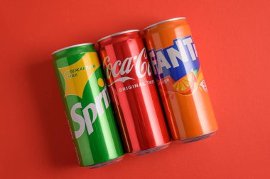 Lviv, Ukrayna - 25 Mart 2025: Kırmızı zemin üzerinde demir Coca Cola, Fanta ve Sprite kutuları. Üst görünüm