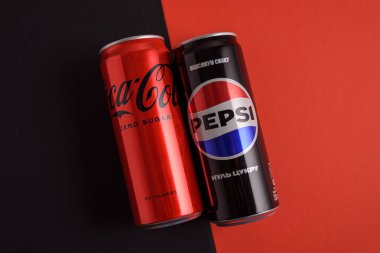 Lviv, Ukrayna - 25 Mart 2025: Kırmızı arka planda demir kutular dolusu Coca Cola ve Pepsi sıfır şeker. Üst görünüm