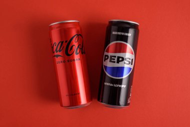 Lviv, Ukrayna - 25 Mart 2025: Kırmızı arka planda demir kutular dolusu Coca Cola ve Pepsi sıfır şeker. Üst görünüm