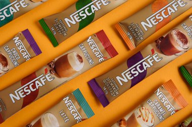 Lviv, Ukrayna - 28 Mart 2025: Nescafe Sachet hazır kahve farklı tatlar: Latte, Cappuccino, İrlanda, Choco ve Karamel sarı arka planda. Üst görünüm