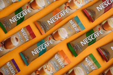 Lviv, Ukrayna - 28 Mart 2025: Nescafe Sachet hazır kahve farklı tatlar: Latte, Cappuccino, İrlanda, Choco ve Karamel sarı arka planda. Üst görünüm