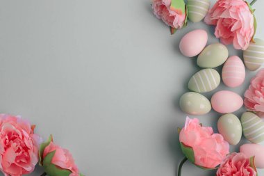 Paskalya yumurtaları ve pastel arka planda bahar çiçekleri. Üst görünüm