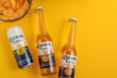 Lviv, Ukrayna - 22 Nisan 2025: Corona Extra bira şişeleri ve sarı arka planda cips kutuları. Üst görünüm