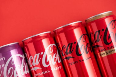 Lviv, Ukrayna - 05 Mayıs 2025: Coca Cola 'nın demir kutuları: klasik, sıfır şeker, sıfır şeker sıfır kafein, kırmızı arka planda kiraz aroması. Üst görünüm