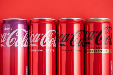 Lviv, Ukrayna - 05 Mayıs 2025: Coca Cola 'nın demir kutuları: klasik, sıfır şeker, sıfır şeker sıfır kafein, kırmızı arka planda kiraz aroması. Üst görünüm