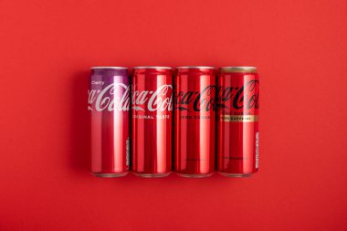 Lviv, Ukrayna - 05 Mayıs 2025: Coca Cola 'nın demir kutuları: klasik, sıfır şeker, sıfır şeker sıfır kafein, kırmızı arka planda kiraz aroması. Üst görünüm