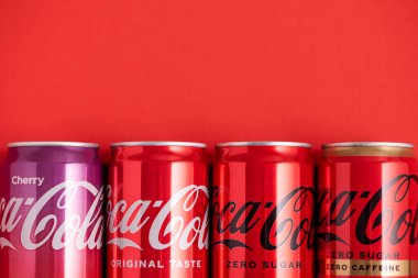 Lviv, Ukrayna - 05 Mayıs 2025: Coca Cola 'nın demir kutuları: klasik, sıfır şeker, sıfır şeker sıfır kafein, kırmızı arka planda kiraz aroması. Üst görünüm