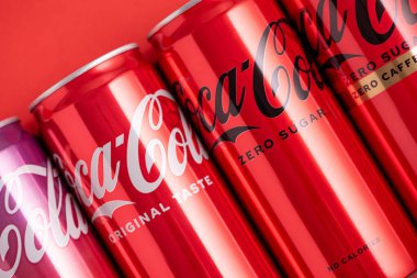 Lviv, Ukrayna - 05 Mayıs 2025: Coca Cola 'nın demir kutuları: klasik, sıfır şeker, sıfır şeker sıfır kafein, kırmızı arka planda kiraz aroması. Üst görünüm