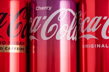 Lviv, Ukrayna - 05 Mayıs 2025: Coca Cola 'nın demir kutuları: klasik, sıfır şeker, sıfır şeker sıfır kafein, kırmızı arka planda kiraz aroması. Üst görünüm
