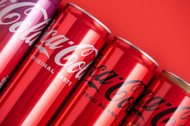 Lviv, Ukrayna - 05 Mayıs 2025: Coca Cola 'nın demir kutuları: klasik, sıfır şeker, sıfır şeker sıfır kafein, kırmızı arka planda kiraz aroması. Üst görünüm