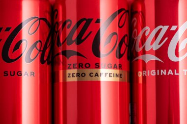 Lviv, Ukrayna - 05 Mayıs 2025: Coca Cola 'nın demir kutuları: klasik, sıfır şeker, sıfır şeker sıfır kafein, kırmızı arka planda kiraz aroması. Üst görünüm